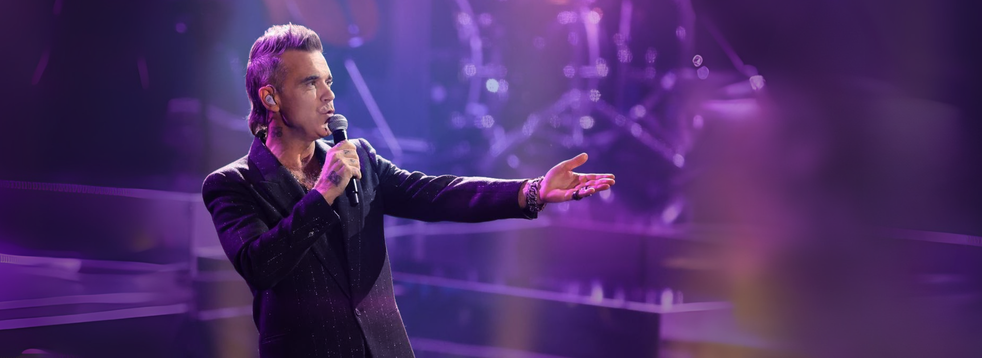 Robbie Williams smiling. He is with microphone in his hand. EVENTURIA